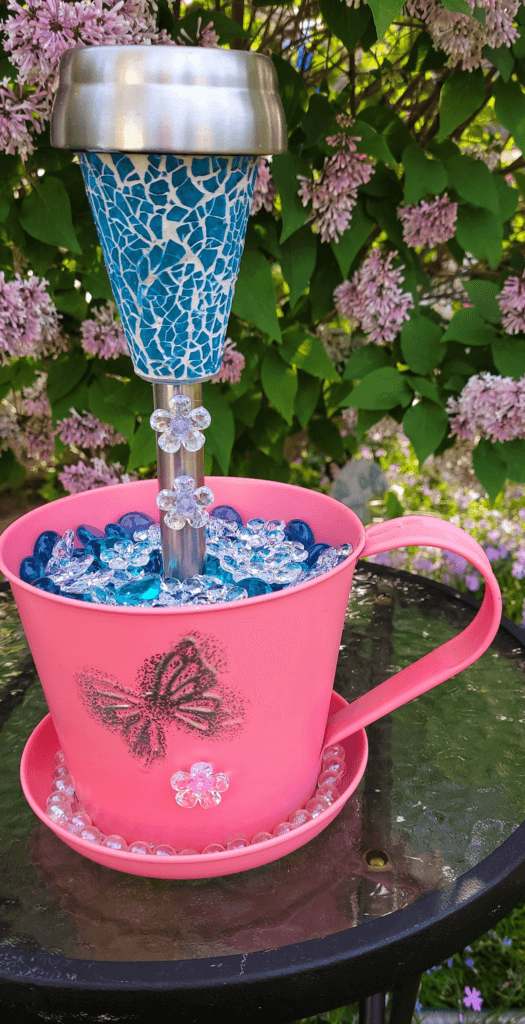 Detailed view of a DIY garden ornament with a solar light in a decorated metal bucket.