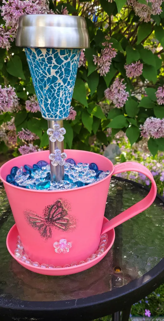 Detailed view of a DIY garden ornament with a solar light in a decorated metal bucket.