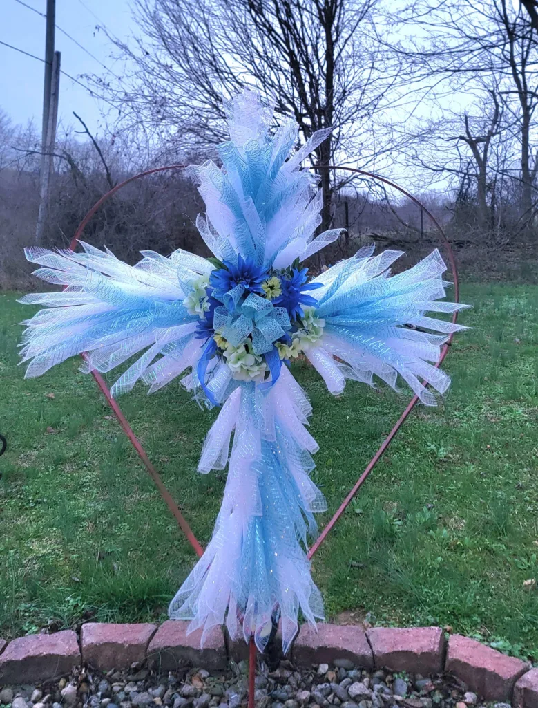 DIY memorial garden cross made with Dollar Tree items, featuring flowers and mesh ribbons.