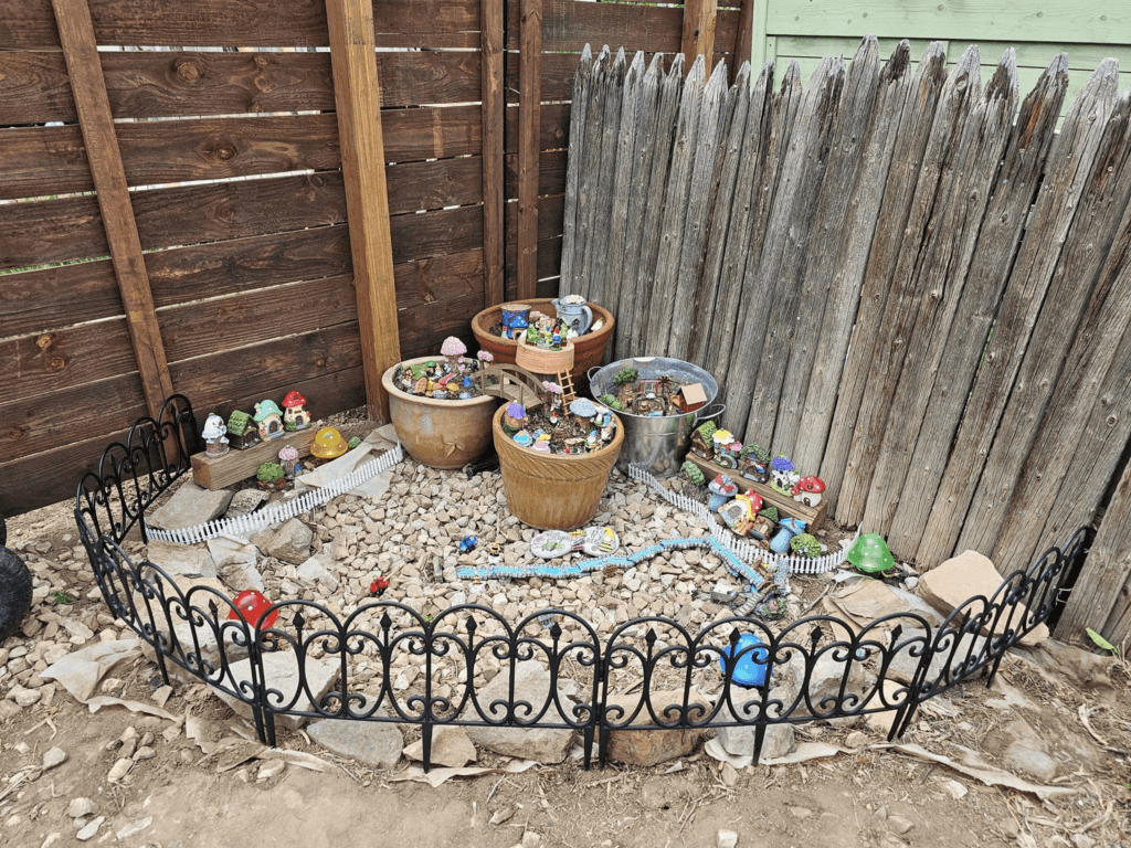 An enchanting gnome and fairy garden with various pots and decorations, mostly from Dollar Tree.