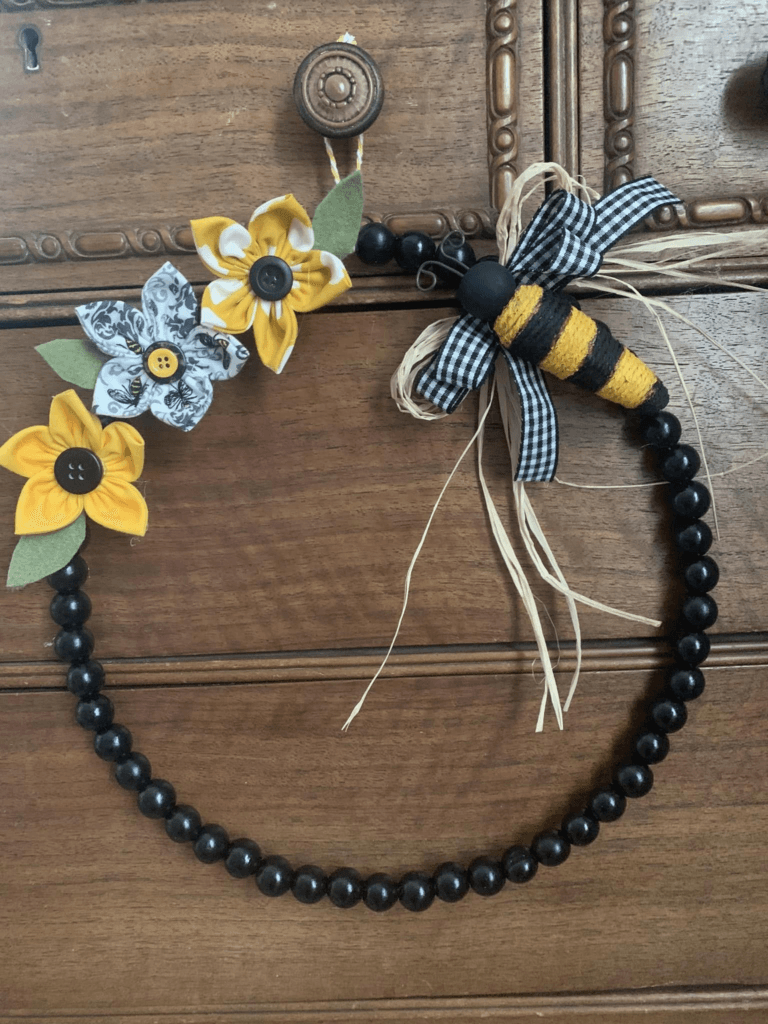 handmade bee and fabric flowers on a beaded wreath.