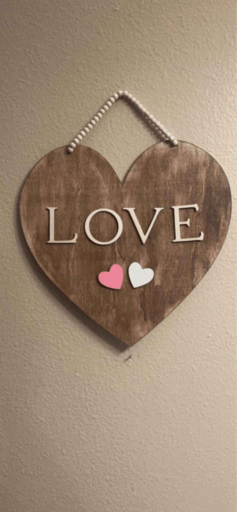 A DIY wooden heart wall hanging with "LOVE" letters and a beaded hanger