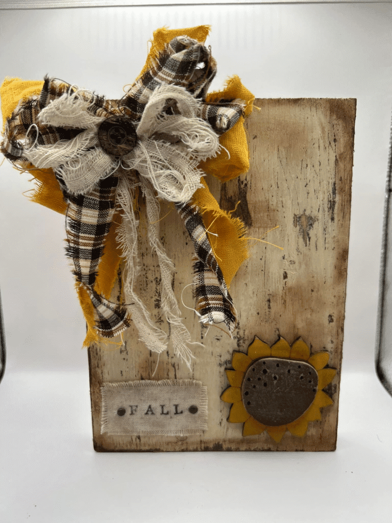 DIY rustic fall wood block decor with distressed paint, plaid and burlap bow, sunflower accent, and fabric Fall label