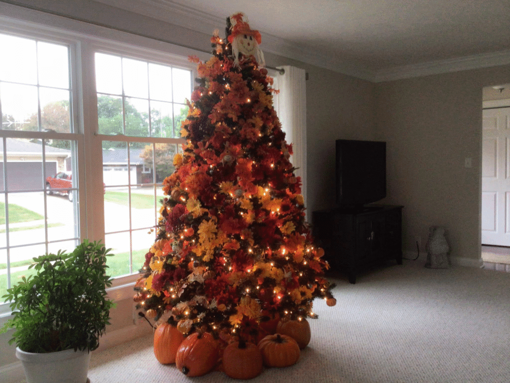 Fall-themed Christmas tree decorated with autumn leaves, pumpkins, and warm string lights