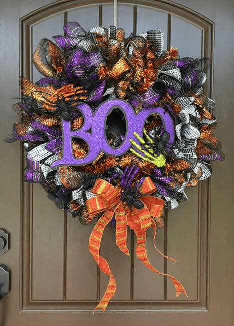 DIY Halloween mesh wreath with glittery BOO sign, skeleton hands, and colorful mesh ribbon in purple, orange, black, and white